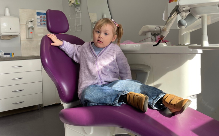 Dziewczynka siedząca na fotelu dentystycznym w gabinecie.