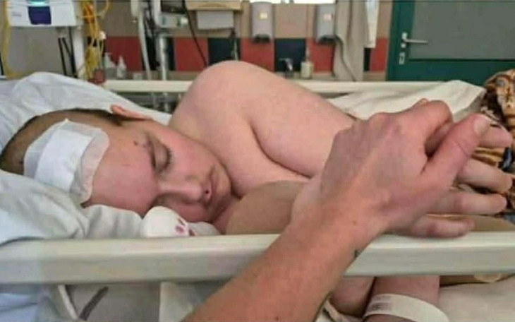 Chłopiec w szpitalu, trzymany za rękę przez bliską osobę.