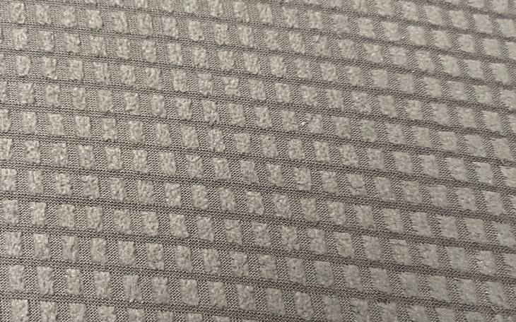 Zbliżenie na szary materiał z wyraźnym wzorem.