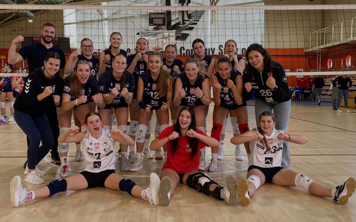 Zespół siatkarski pozujący do zdjęcia po zwycięstwie na boisku.