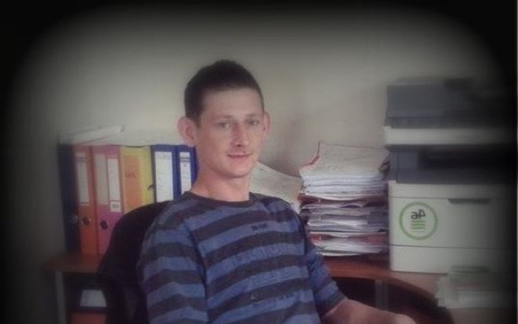 Mężczyzna siedzący przy biurku, otoczony dokumentami.