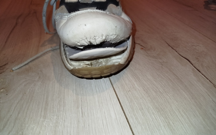 Zniszczony but sportowy z widoczną dziurą.
