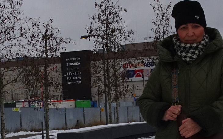 Kobieta w zimowej kurtce, stojąca przed budynkiem.