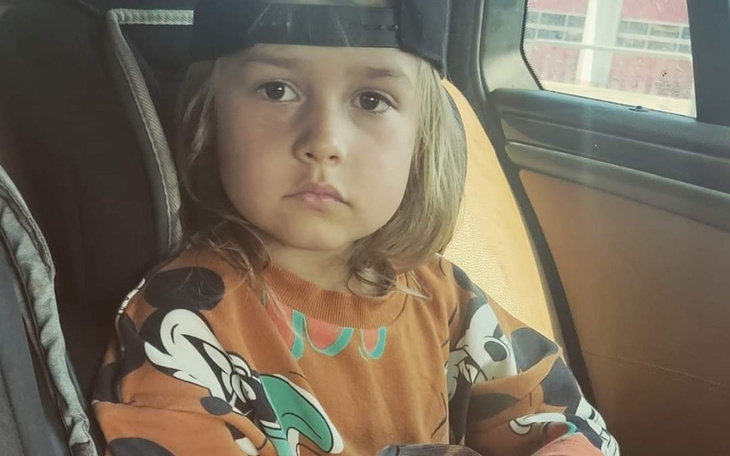 Chłopiec w samochodzie, z poważnym wyrazem twarzy, w kolorowej bluzie i czapce.