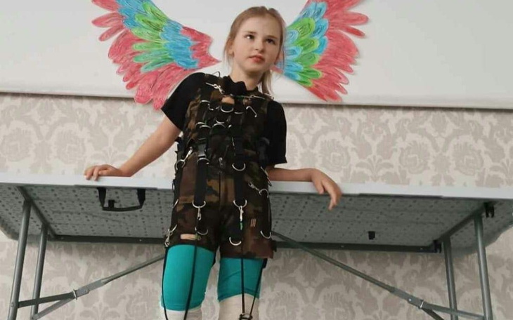 Dziewczynka w specjalnym stroju z kolorowymi skrzydłami.