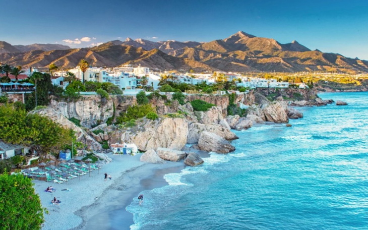 Malowniczy widok na plażę i góry w tle.