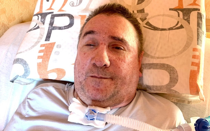 Mężczyzna leżący na łóżku, z rurką do oddychania.