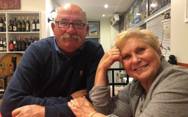 Uśmiechnięta para siedzi przy stole w restauracji.