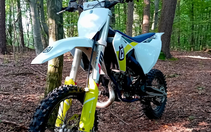 Motocykl terenowy w lesie, otoczony drzewami.