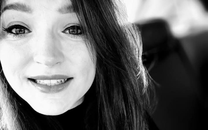 Portret uśmiechniętej kobiety w czarno-białym ujęciu.