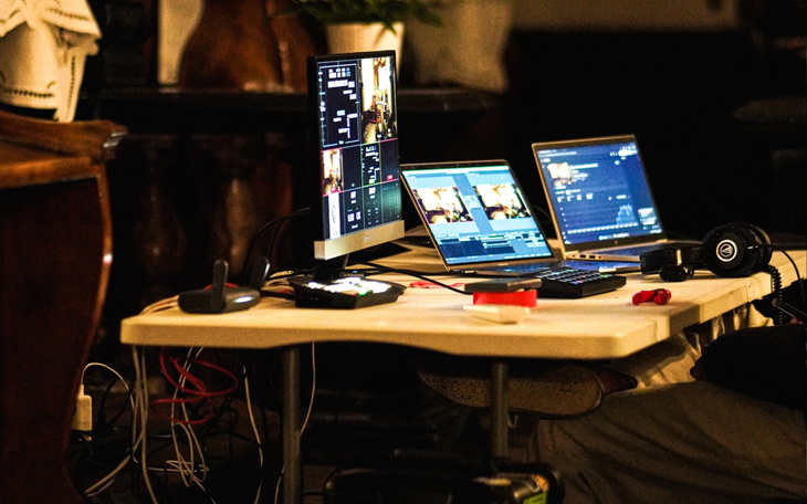 Stół z komputerami do transmisji na żywo, z ekranami i sprzętem.