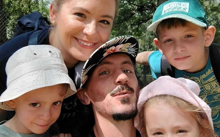 Rodzina na zdjęciu, uśmiechnięta w plenerze, z dziećmi.