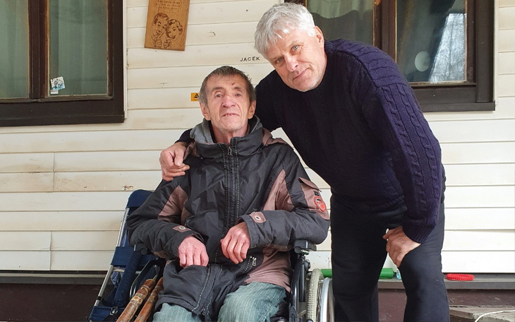 Mężczyzna w towarzystwie starszego pana na wózku inwalidzkim.