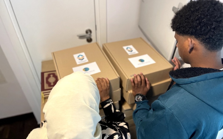 Dwie osoby trzymające pudełka z logo fundacji.