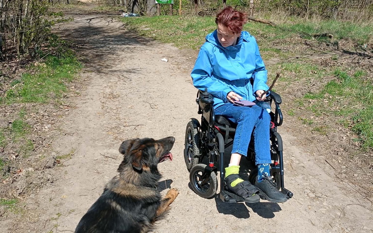 Kobieta na wózku inwalidzkim spacerująca z psem.