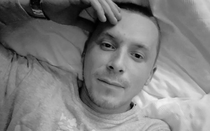Mężczyzna leżący na łóżku, z ręką na czole.