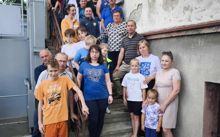 Grupa ludzi na schodach, uśmiechnięci i zadowoleni.