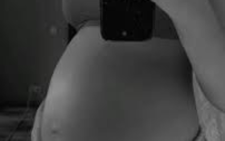 Czarno-białe zdjęcie brzucha kobiety w ciąży.