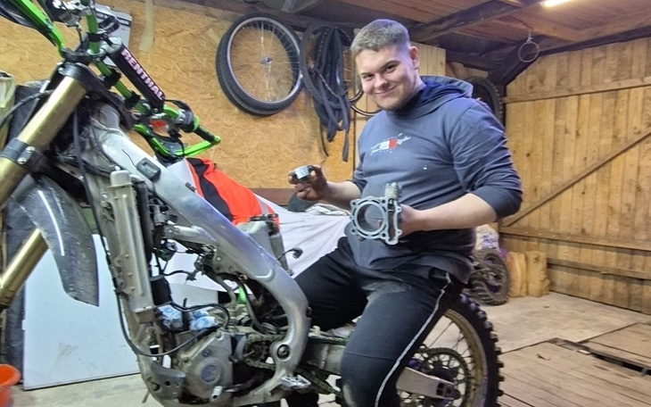 Mężczyzna trzymający części motocykla w warsztacie.