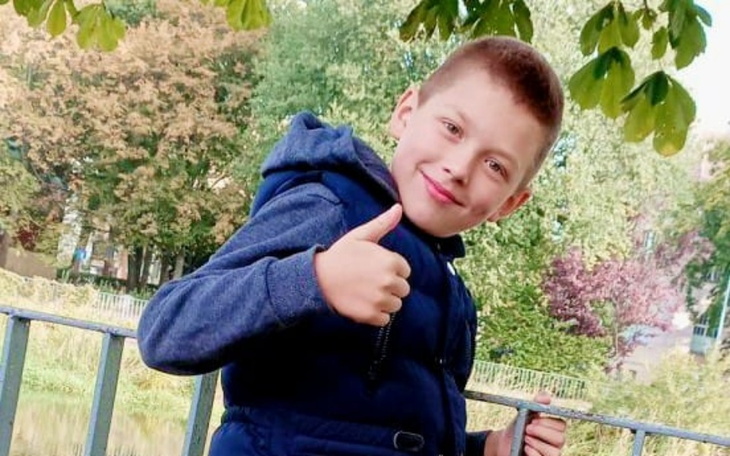 Dwaj chłopcy w wózkach inwalidzkich przed budynkiem.