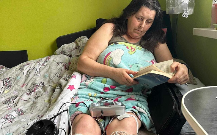 Kobieta czytająca książkę w łóżku, otulona kocem.