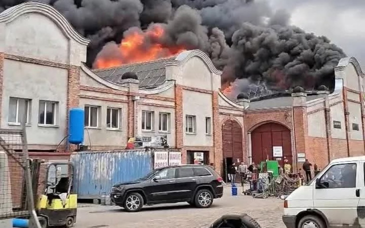Pożar w budynku, gęsty dym i płomienie wydobywające się z dachu.