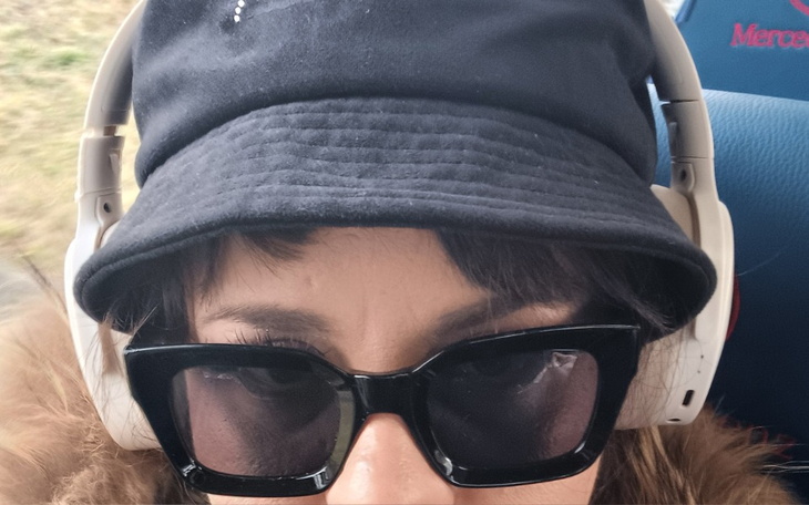 Osoba w okularach przeciwsłonecznych i słuchawkach.