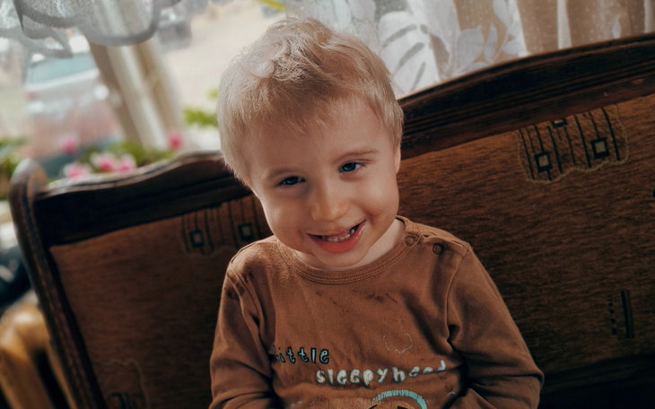 Uśmiechnięty chłopiec siedzący na kanapie, pełen radości.