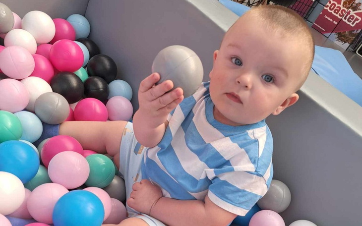 Mały chłopiec bawi się w basenie z kolorowymi piłkami.