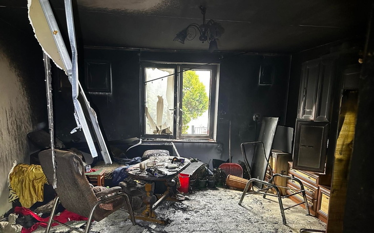 Zniszczony pokój po pożarze, z popiołem i zniszczeniami.