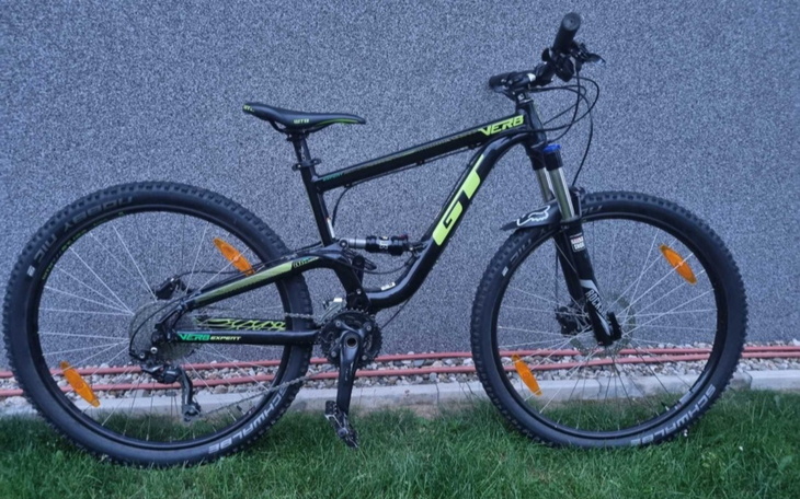 Rower górski w kolorze czarnym i zielonym, stojący na trawie.