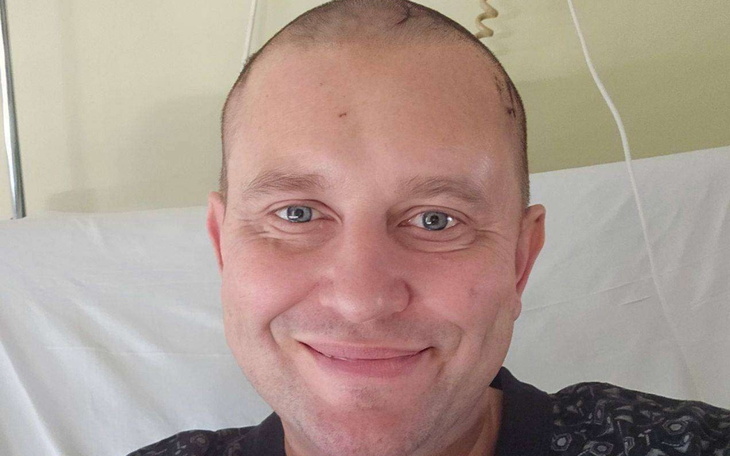 Mężczyzna z uśmiechem, w szpitalnym łóżku, z nadzieją na zdrowie.