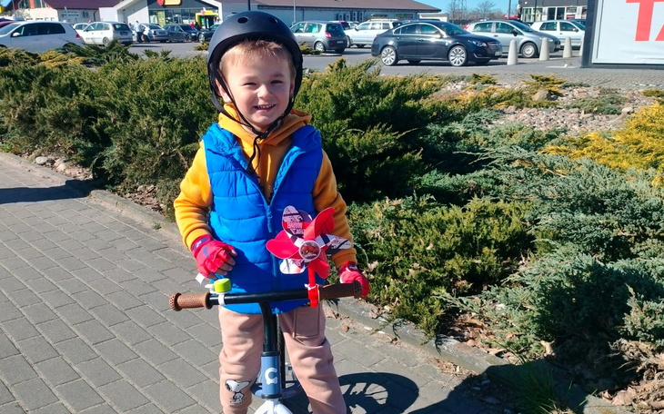 Chłopiec na hulajnodze, uśmiechnięty i pełen energii.