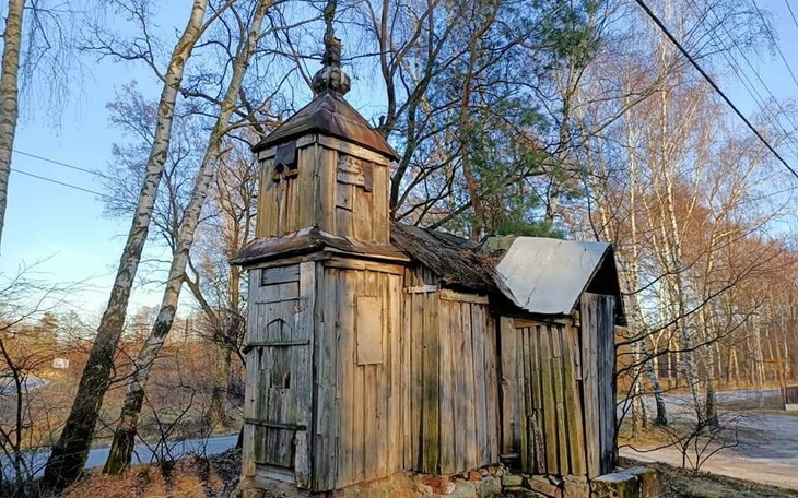 Stara, drewniana kapliczka w lesie.