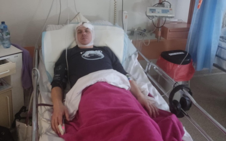 Mężczyzna w szpitalnym łóżku, z opatrunkiem na głowie.