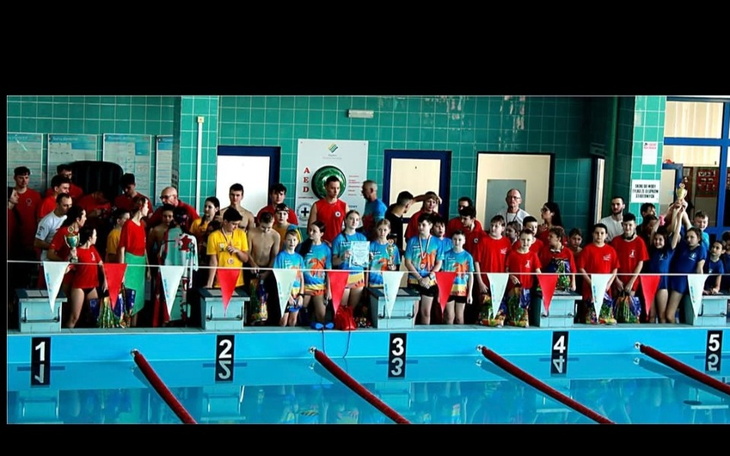 Grupa dzieci i dorosłych na basenie, gotowych do zawodów.