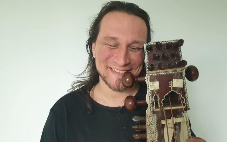 Mężczyzna trzymający instrument muzyczny, uśmiechający się.