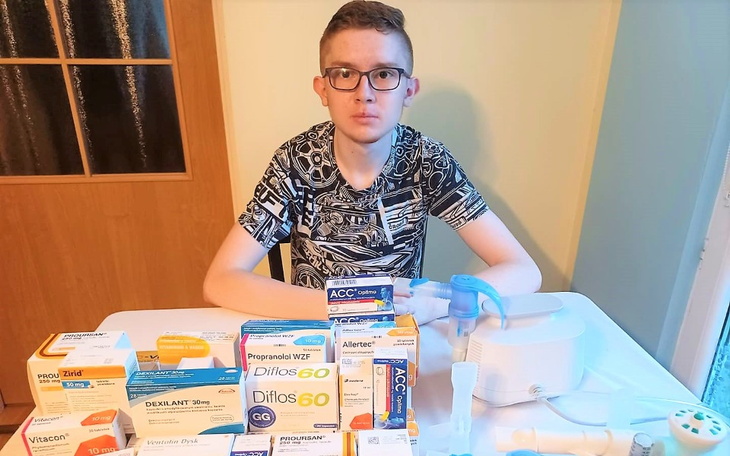 Młody mężczyzna siedzący przy stole z lekami.