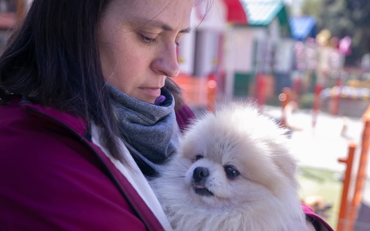 Kobieta trzyma w ramionach małego psa rasy pomeranian.