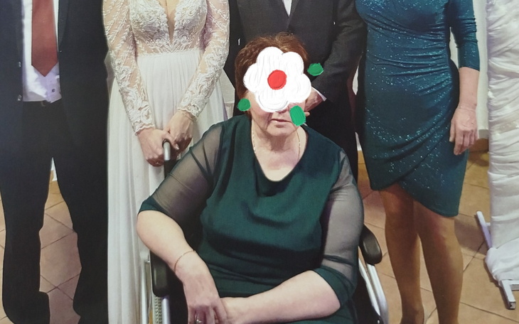 Grupa ludzi na uroczystości, jedna osoba na wózku.