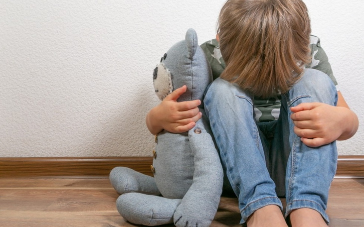 Chłopiec siedzący na podłodze z pluszowym misiem.