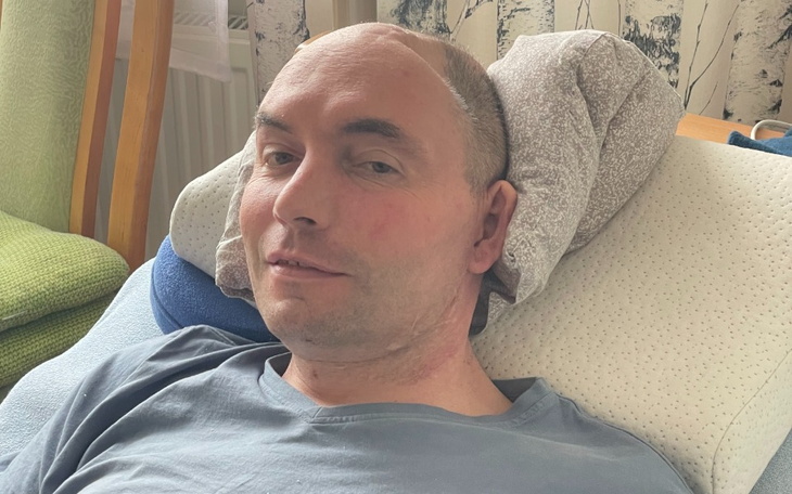 Mężczyzna leżący na łóżku, z widocznymi obrażeniami.