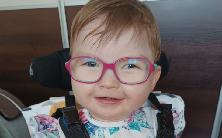 Mała dziewczynka w okularach, uśmiechająca się do kamery.