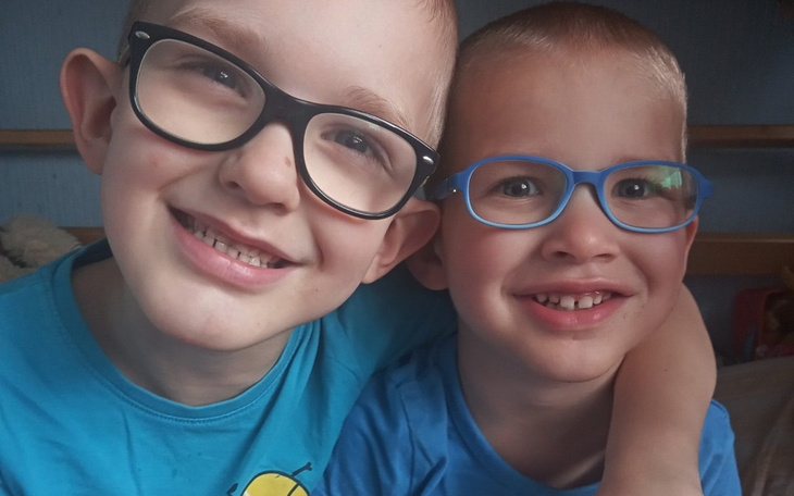 Dwóch chłopców w okularach, uśmiechających się do kamery.
