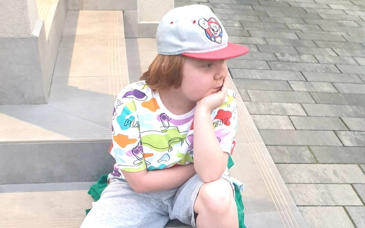 Chłopiec w kolorowej koszulce, siedzący na schodach.