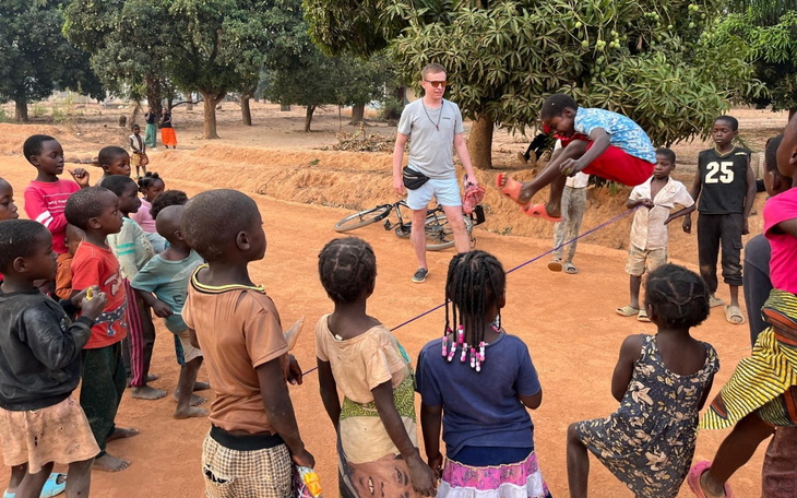 Dzieci bawiące się z dorosłym na podwórku w Afryce.