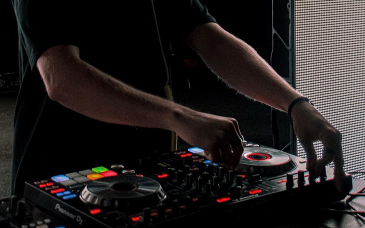 DJ miksujący muzykę, z bliskim ujęciem rąk na sprzęcie.