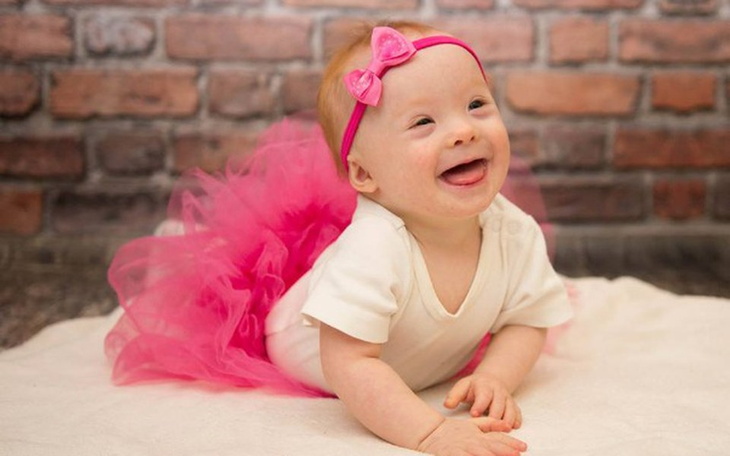 Mała dziewczynka w różowej spódniczce, uśmiechająca się szeroko.