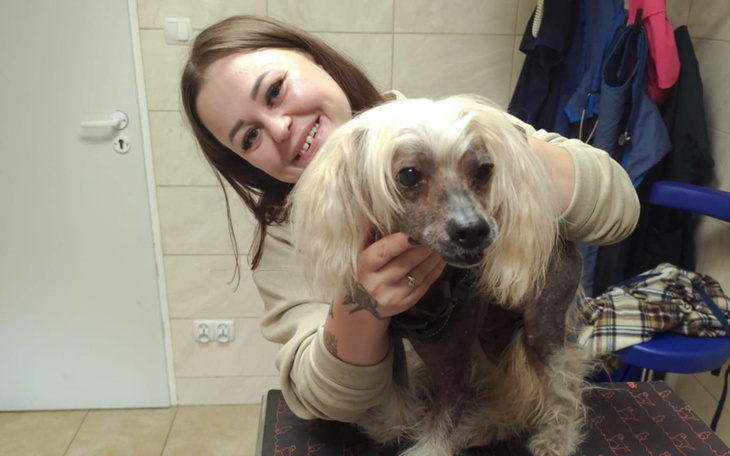 Uśmiechnięta kobieta trzymająca psa w weterynarii.