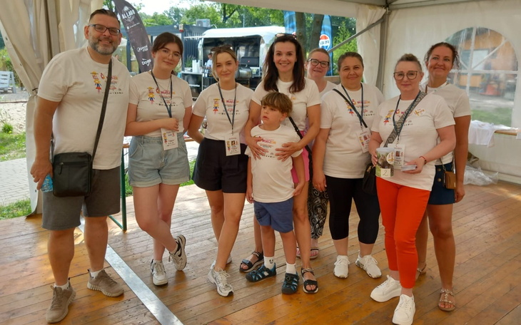 Grupa ludzi w koszulkach na wydarzeniu, uśmiechnięci i zadowoleni.